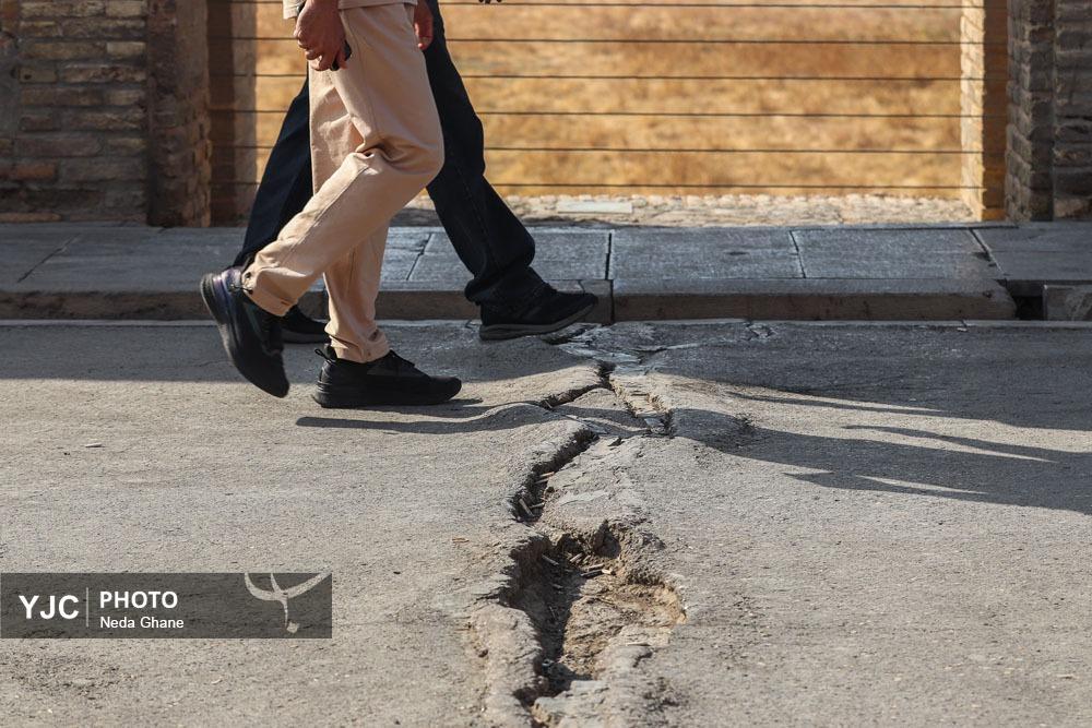 نمای نزدیک از شکاف‌های ناشی از فرونشست زمین در بناهای تاریخی و خیابان‌های اصفهان که نشان‌دهنده آسیب به زیرساخت‌ها و میراث فرهنگی است.