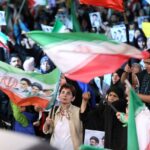 عکس | یک تصویر متفاوت؛ زن سلاح‌بدست روی موتور پشت سر نیروی نظامی در کنار پرچم جمهوری اسلامی ایران