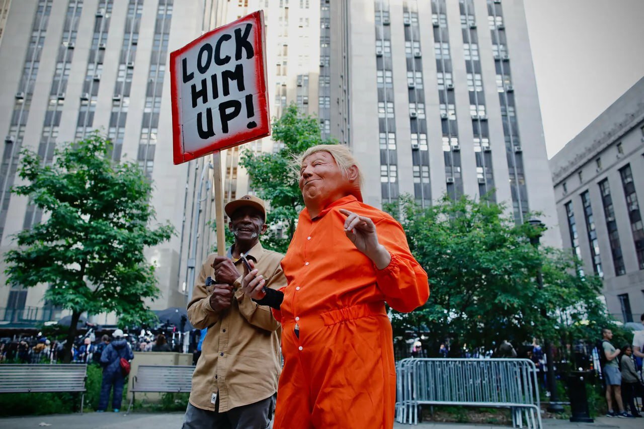عکس | تصویر ترامپ با لباس زندانی در خیابان‌های آمریکا و یک پلاکارد!
