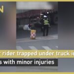 ببینید | لحظه وحشتناک سقوط یک زن زیر چرخ‌های تریلی مقابل چشمان پلیس؛ فریادها بلند شد